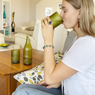 A hand holding the eco-friendly Woodlands Collection pint glass, capturing the artisanal green hues and luxurious finish