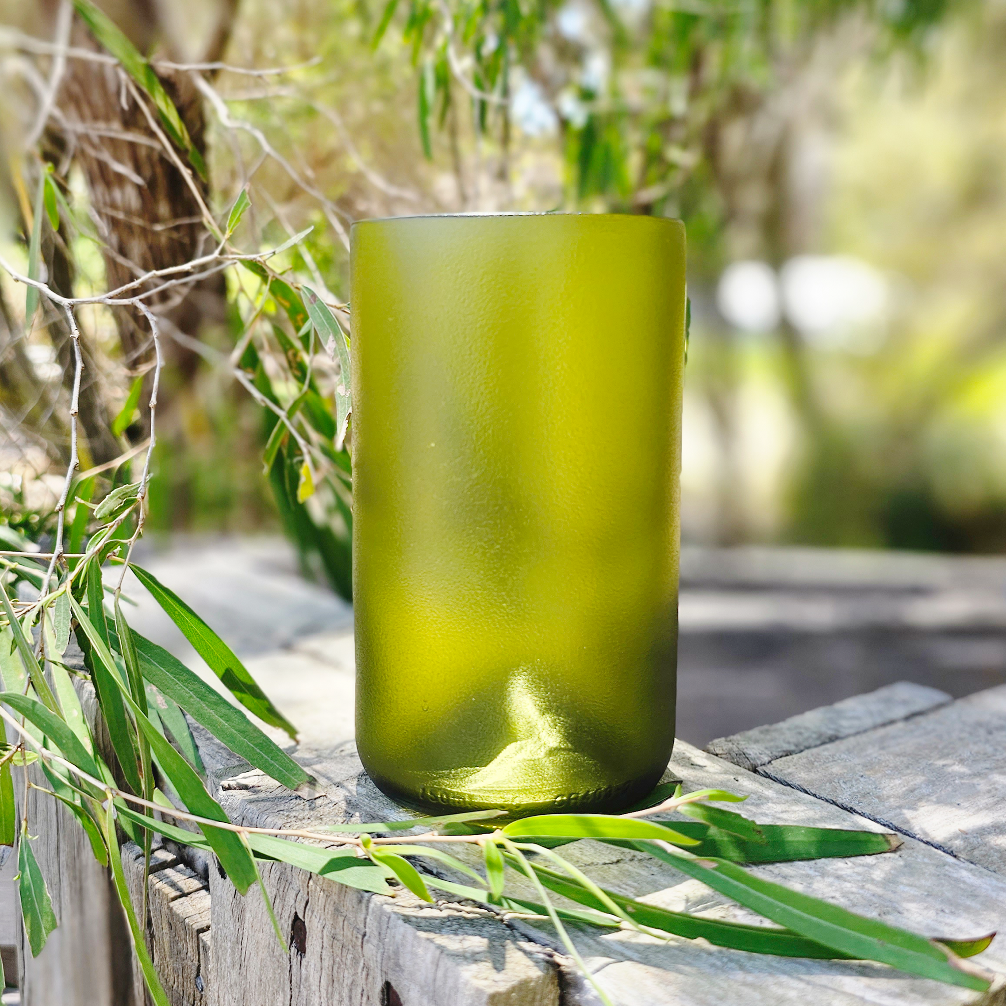 "Sustainable ReValued Glass Pint, bordeaux bottle crafted design, displayed amidst natural Woodlands elements for an eco-lux aesthetic."