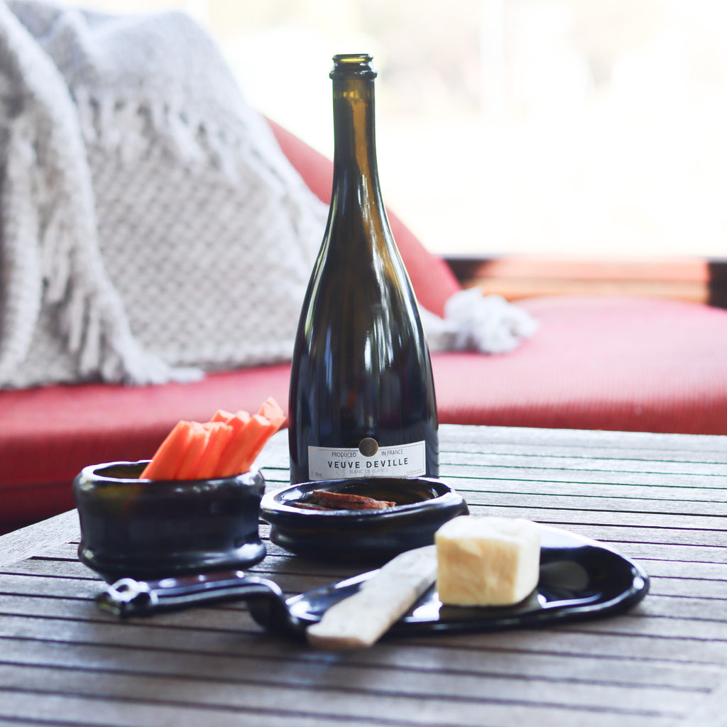 The elegant Prestige Organic Punt Dish as a centerpiece on a modern dining setup, showcasing its versatility and sophisticated flair. Includes the source sparkling bottle that gives it's provenance.