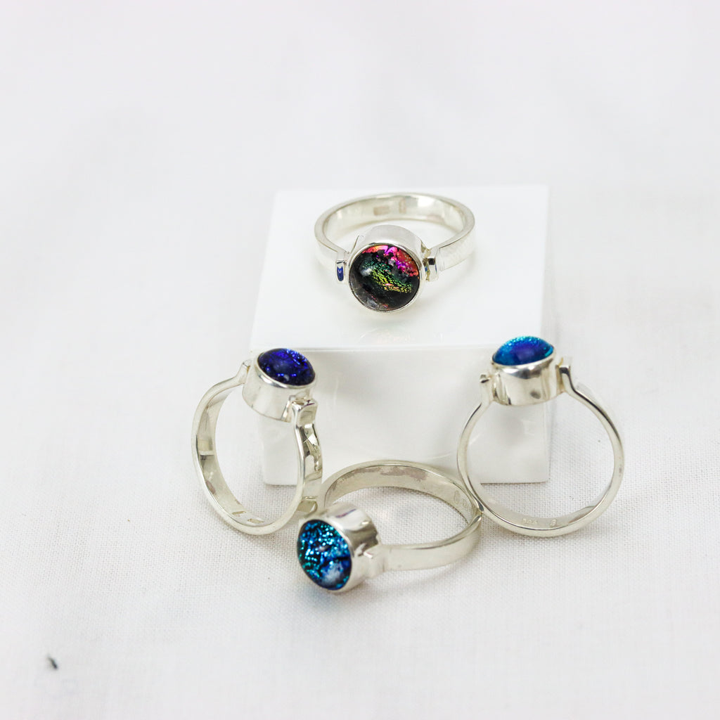 The Ivy Ring collection beautifully presented on a marble block. The colours of lake Hillier, Twilight Deep Water, Twilight beach shallow water and Hellfire Bay, Close up of  different views showing the sterling silver band cradling the glass gem and bezel finish.